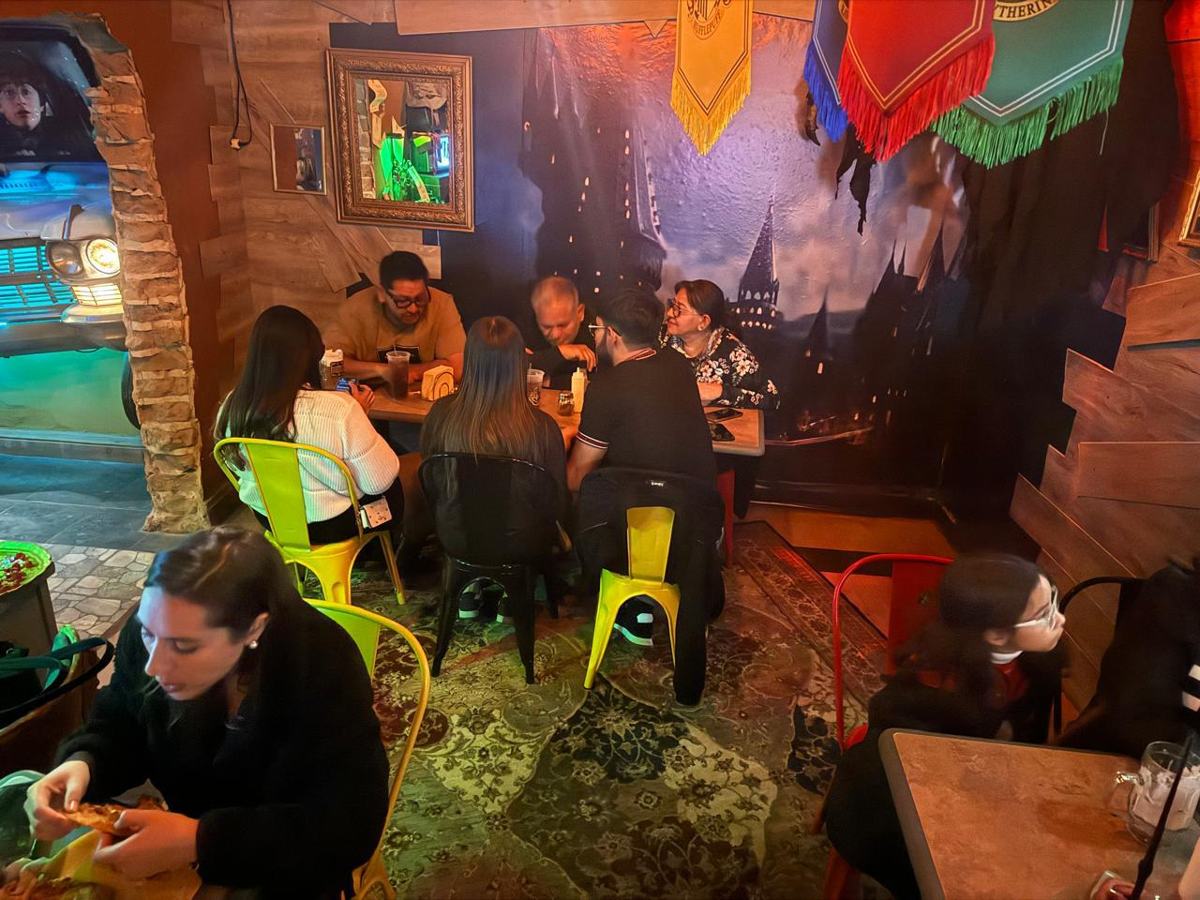 Mesa bajo el mural de Hogwarts con los escudos de las cuatro casas colgando del techo