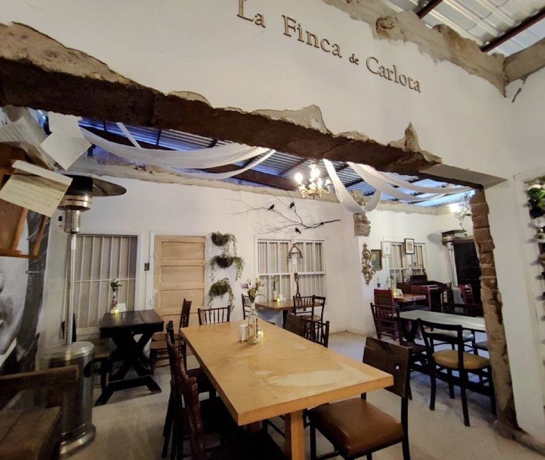 Salón principal con el nombre La Finca de Carlota sobre el muro de piedra